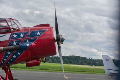 Red airplane on road against sky