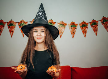 Girl in a halloween hat with pumpkins in her hands.