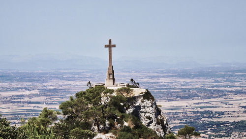 View of cross on building by mountain against sky