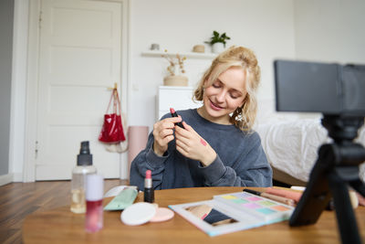 Young woman using mobile phone while sitting on table