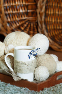 White cup decorated with twine rope and blue dried flower and white wool threads different balls