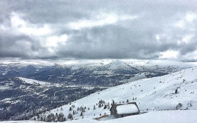 Scenic view of snow covered mountains against cloudy sky