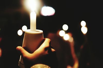 Cropped image of person holding illuminated burning candle