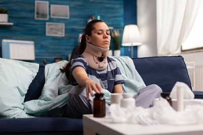 Young woman sitting on bed at home