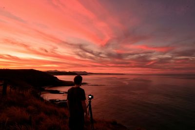 Rear view of man by sea during sunset