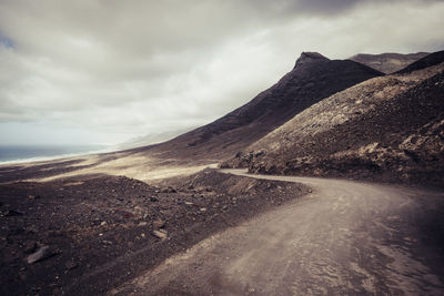 Scenic view of road by mountains against sky