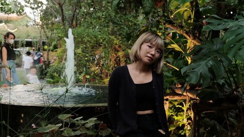 Portrait of young woman standing against plants