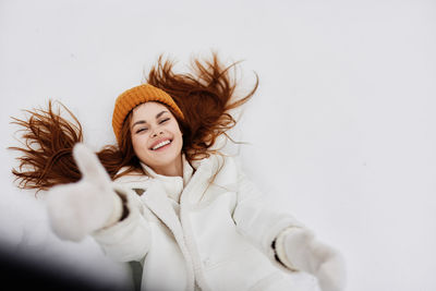 Portrait of smiling woman gesturing by lying on snow