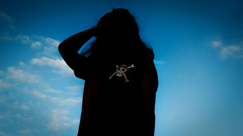 Rear view of woman standing against blue sky