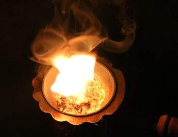 Close-up of hand holding illuminated candle