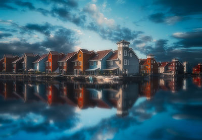 Reflection of buildings in sea against sky