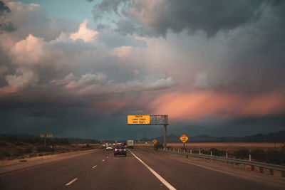 Cars on road against sky during sunset