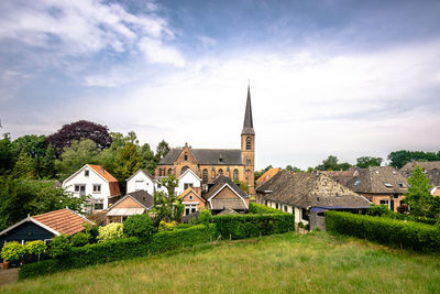 Houses by buildings against sky