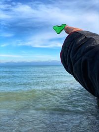 Rear view of person holding sea against sky