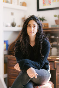 Portrait of woman sitting looking into camera with hair down in home