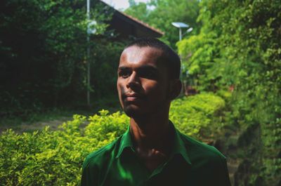 Teenage boy looking away while standing against trees