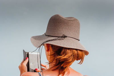 Rear view of woman using smart phone against clear sky