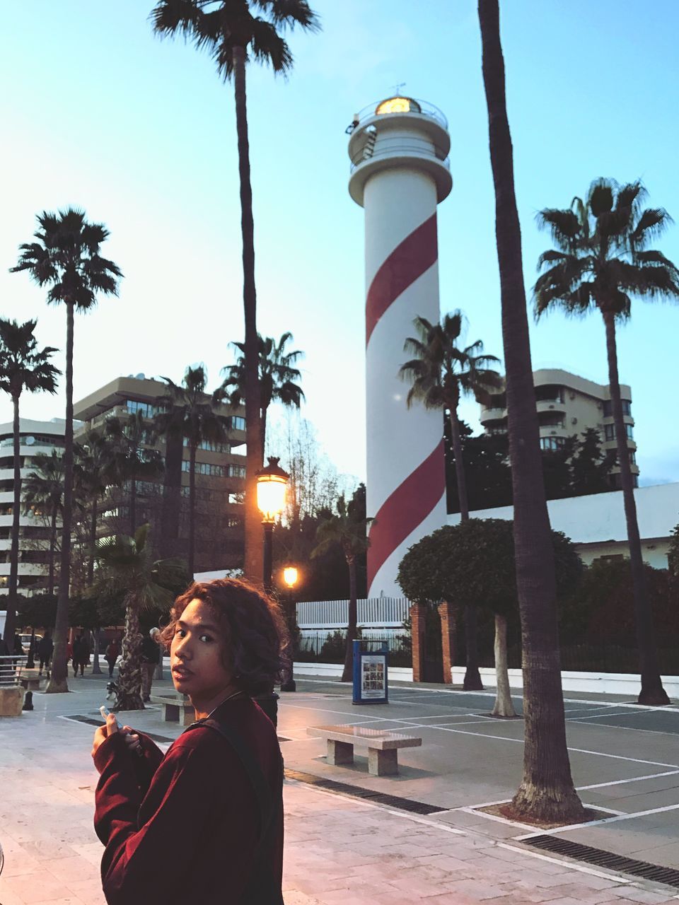 tree, real people, palm tree, one person, outdoors, building exterior, city, built structure, architecture, sky, day, animal themes, young adult, people, adults only, adult