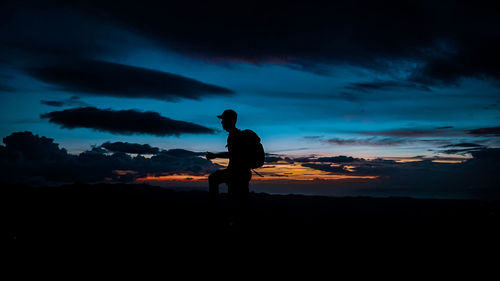 Silhouette man standing on the mountain at sunset
