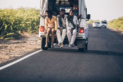 Rear view of people walking on road in city