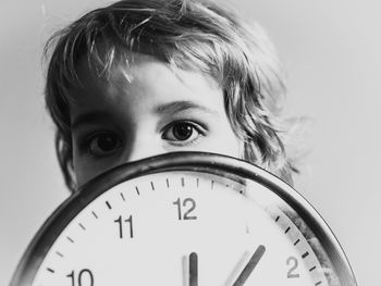 Portrait of boy with wall clock against white background