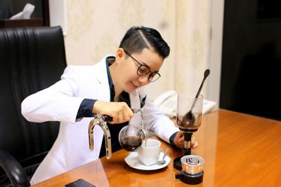 Midsection of woman holding drink in glass on table