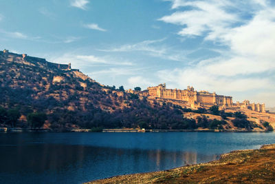 Ancient vintage palace by lake against sky in city