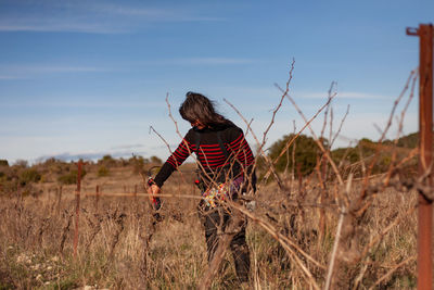 Rear view of woman standing on field against sky