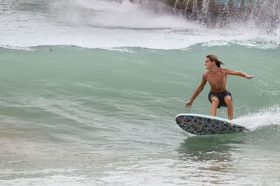 Rear view of boy surfing in sea