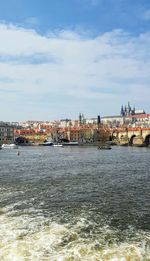 River by buildings in city against sky