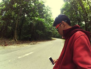 Side view of young man using mobile phone on road