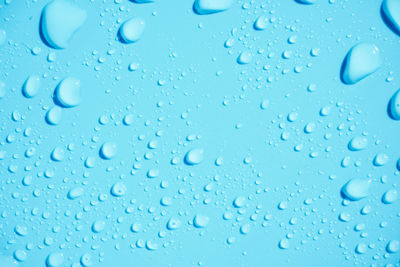 Full frame shot of raindrops on blue glass