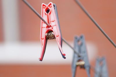 Low angle view of clothespins hanging on metal against wall