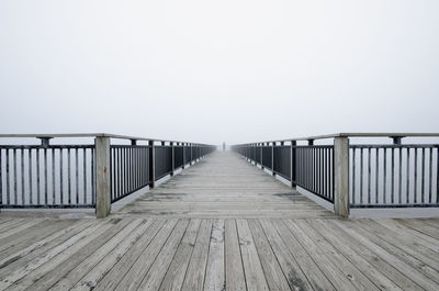 Pier on lake against sky in foggy weather