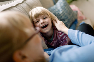 Cheerful boy with grandmother on sofa at home