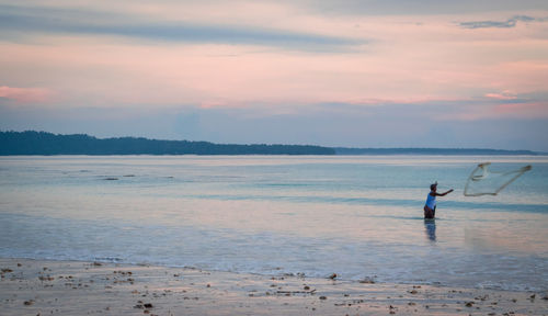 Man on beach against sky during sunset