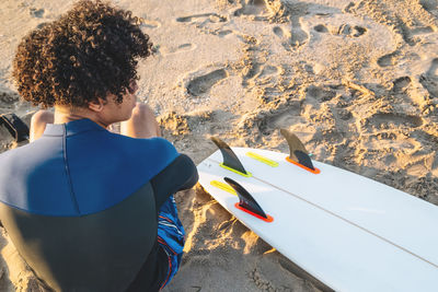 Portrait of young mixed race surfer sitting back to camera.