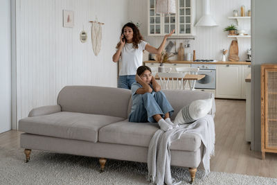 Young woman using laptop while sitting on sofa at home