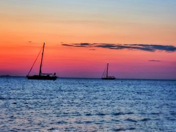 Sailboat sailing on sea against romantic sky at sunset