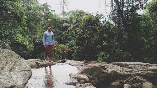Man standing on rock against trees