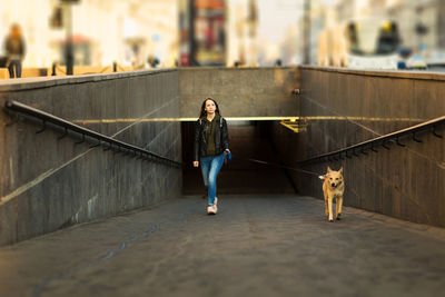 Full length portrait of woman with dog on railing