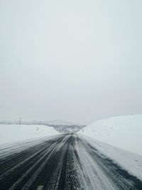 Road amidst snow covered landscape against sky