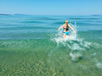 Rear view of woman in bikini walking at beach