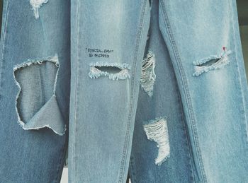 Close-up of torn jeans hanging in store