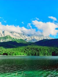 Scenic view of lake and mountains against blue sky