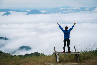 Rear view of woman standing on mountain against sky