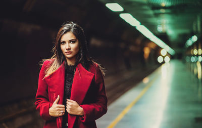 Portrait of young woman standing at railroad station platform