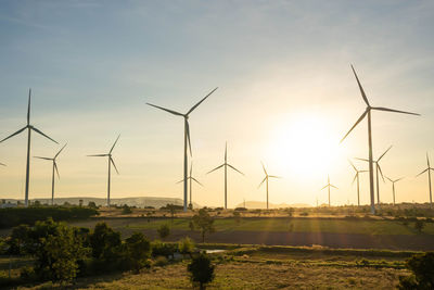 Windmill on field against sky during sunset