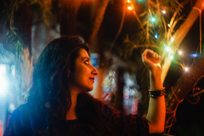 Young woman looking at illuminated light decoration at night