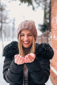 Portrait of smiling young woman in snow during winter